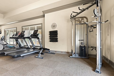 a gym with treadmills and weights in the corner of a room