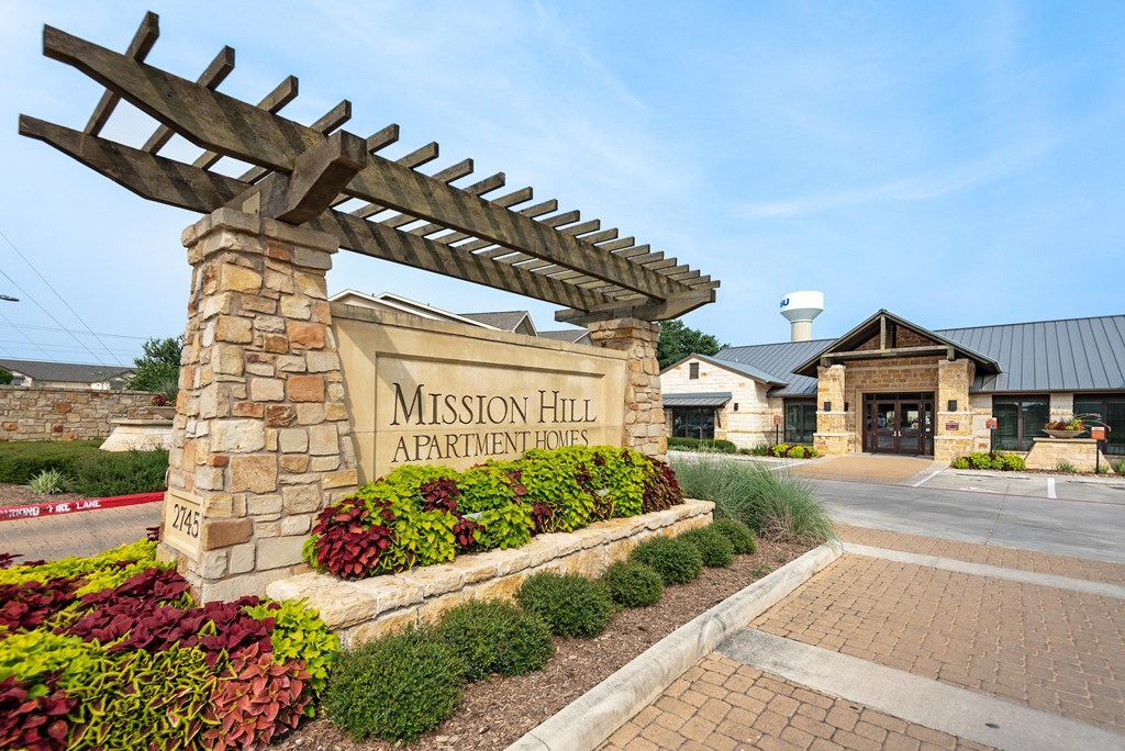 the entrance to mission hill apartments with a stone welcome sign