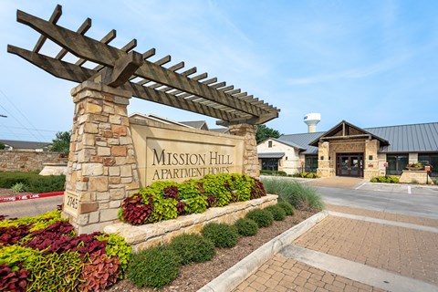 the entrance to mission hill apartments with a stone welcome sign