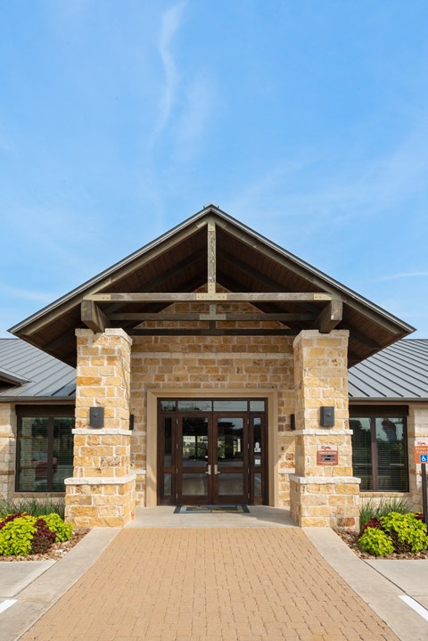 the front entrance of a building with a stone facade and wooden doors