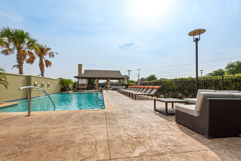 a swimming pool with lounge chairs and a gazebo on a sunny day