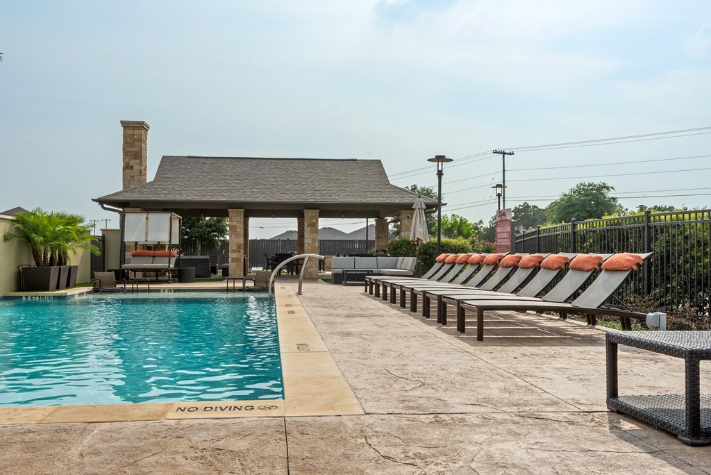 a pool with chairs and a gazebo on the side of a house