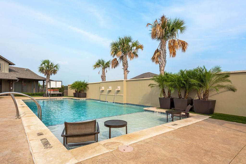 a swimming pool with chairs and palm trees in front of a house