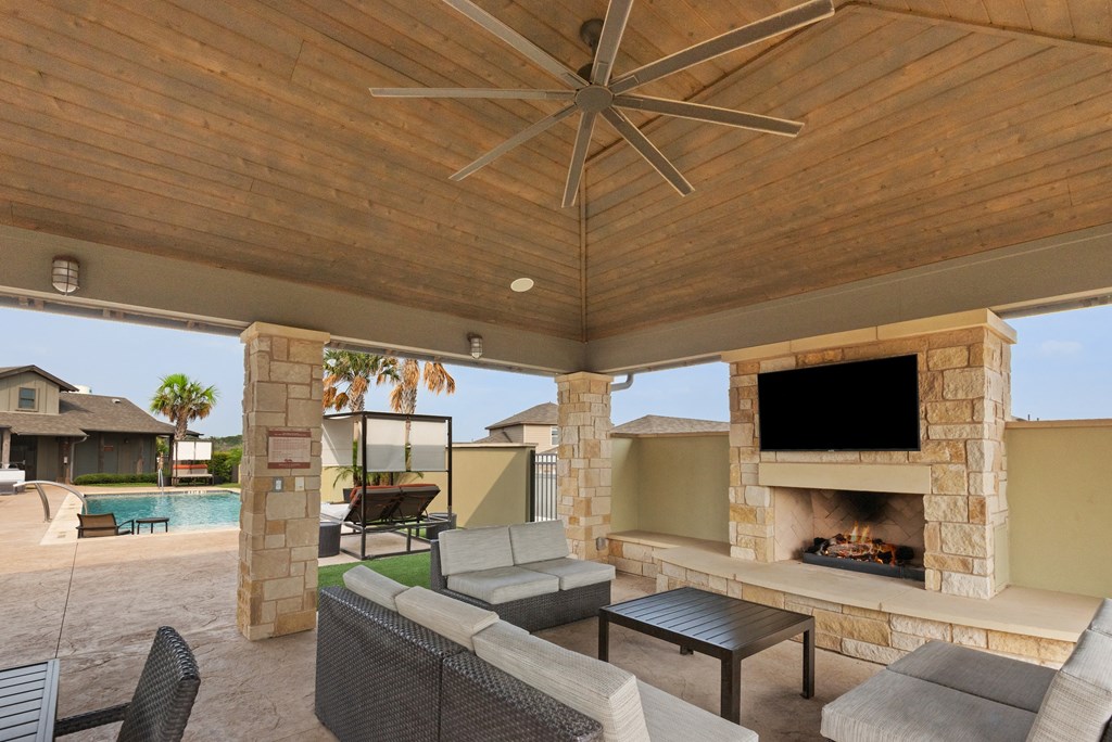 the estates outdoor living area with fireplace and tv