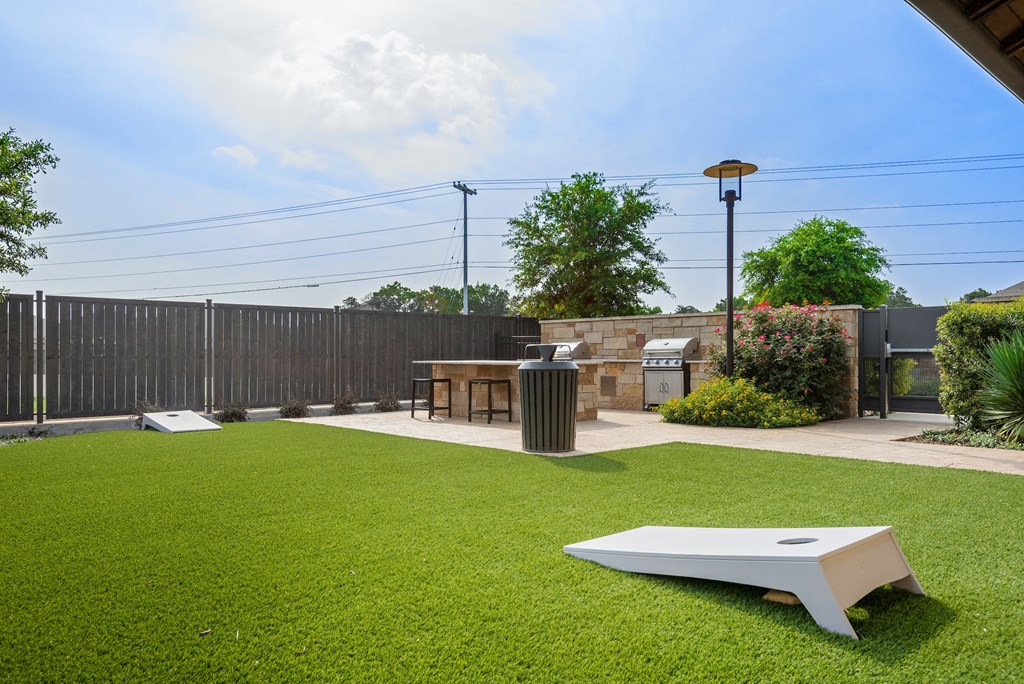 a lawn with a table and a barbecue grill in a backyard