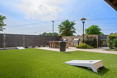 a lawn with a table and a barbecue grill in a backyard