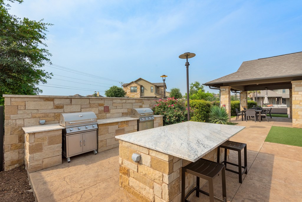 a patio with an outdoor kitchen and a stone wall