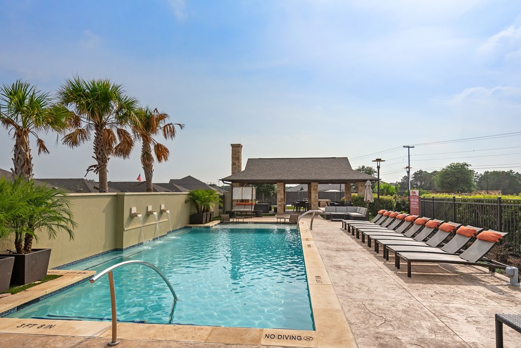 a swimming pool with chairs and a house in the background