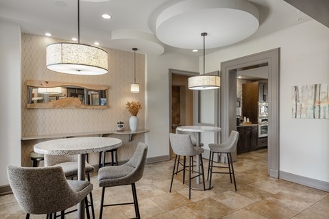 a dining area with tables and chairs and a kitchen in the background