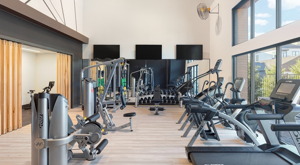 A gym with a variety of equipment including treadmills, stationary bikes, and weight machines.