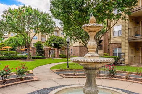 a fountain in the center of a courtyard with apartments in the background