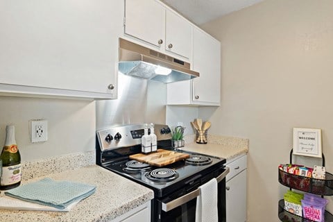 A kitchen with a stove top oven and a white cabinet above it.