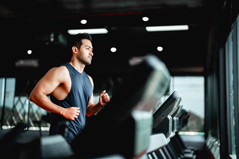A man is running on a treadmill in a gym.