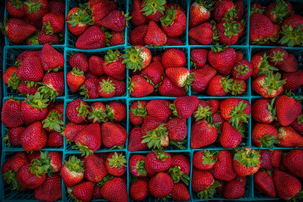 A box of strawberries with green tops.