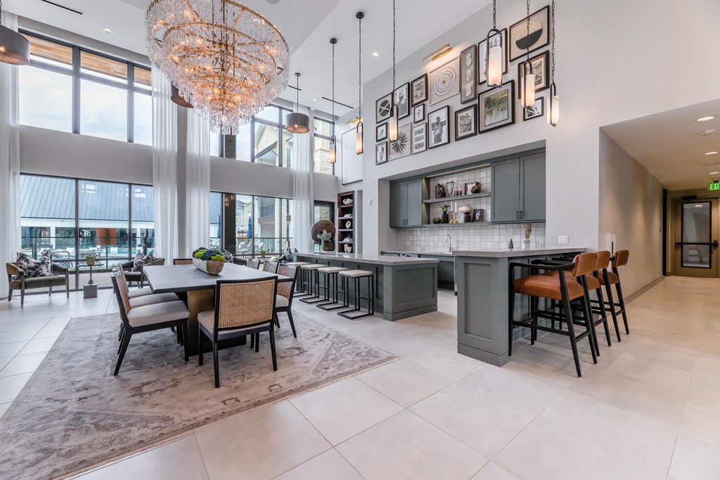 a dining area with a table and chairs and a kitchen with large windows