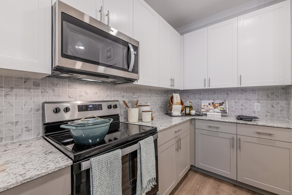 a kitchen with white cabinets and a stove and microwave