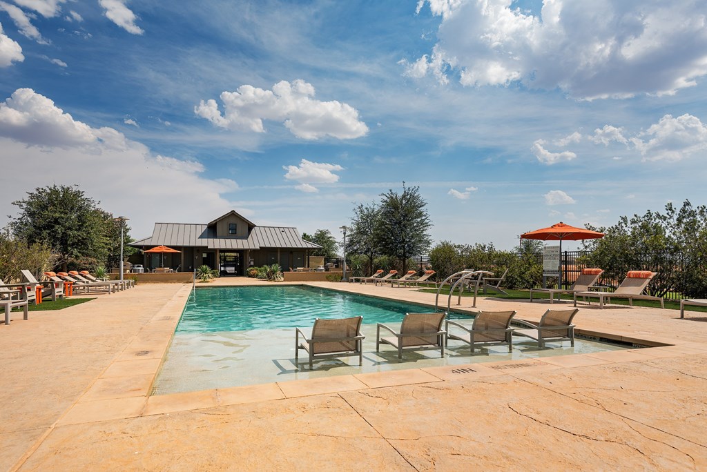 a pool with chairs and a building in the background