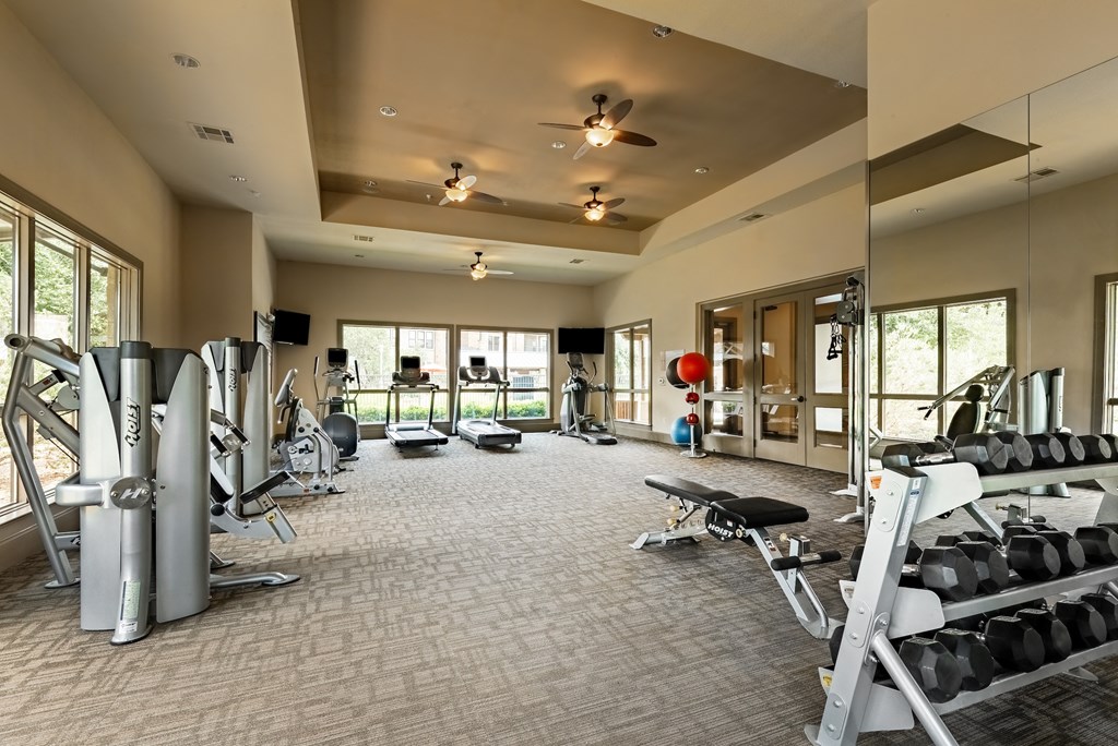 a spacious fitness center with cardio equipment and windows