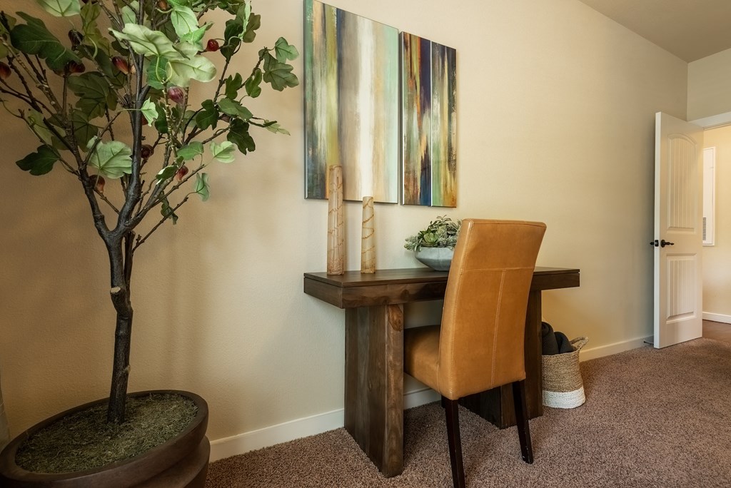 a desk with a plant and a painting on the wall