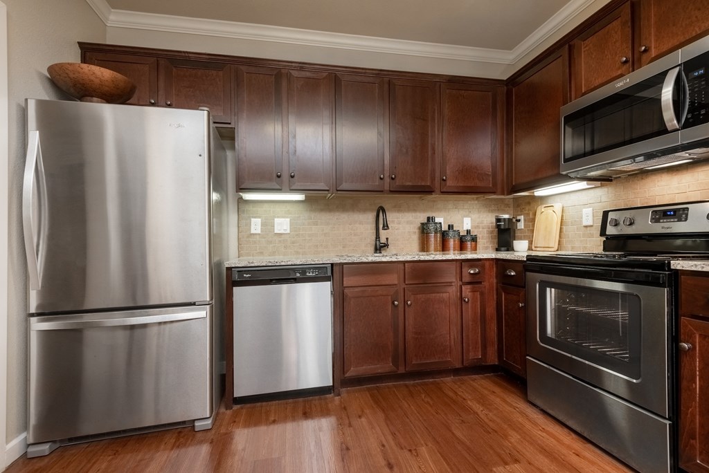 a kitchen with dark wood cabinets and stainless steel appliances
