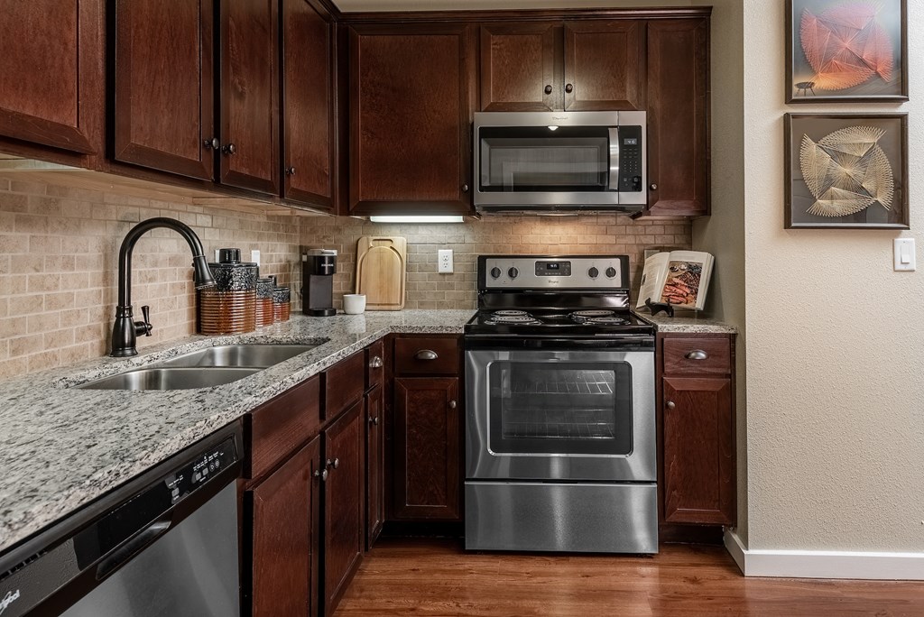 a kitchen with dark wood cabinets and stainless steel appliances