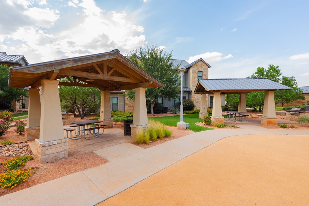 a picnic area with picnic tables and umbrellas at the whispering winds apartments in pearland