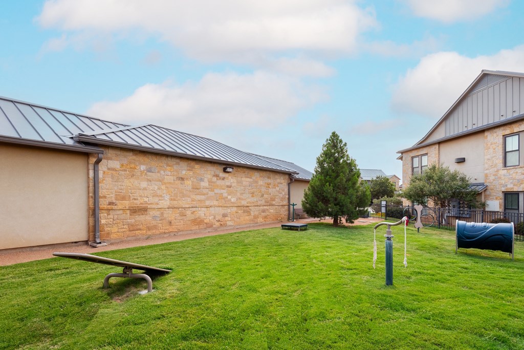 a park with a seesaw and a bench in front of a brick building