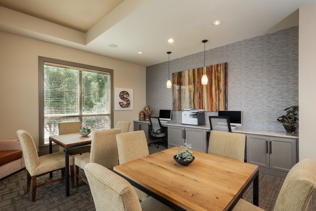 a dining area with a wooden table and chairs and a kitchenette with a countertop and