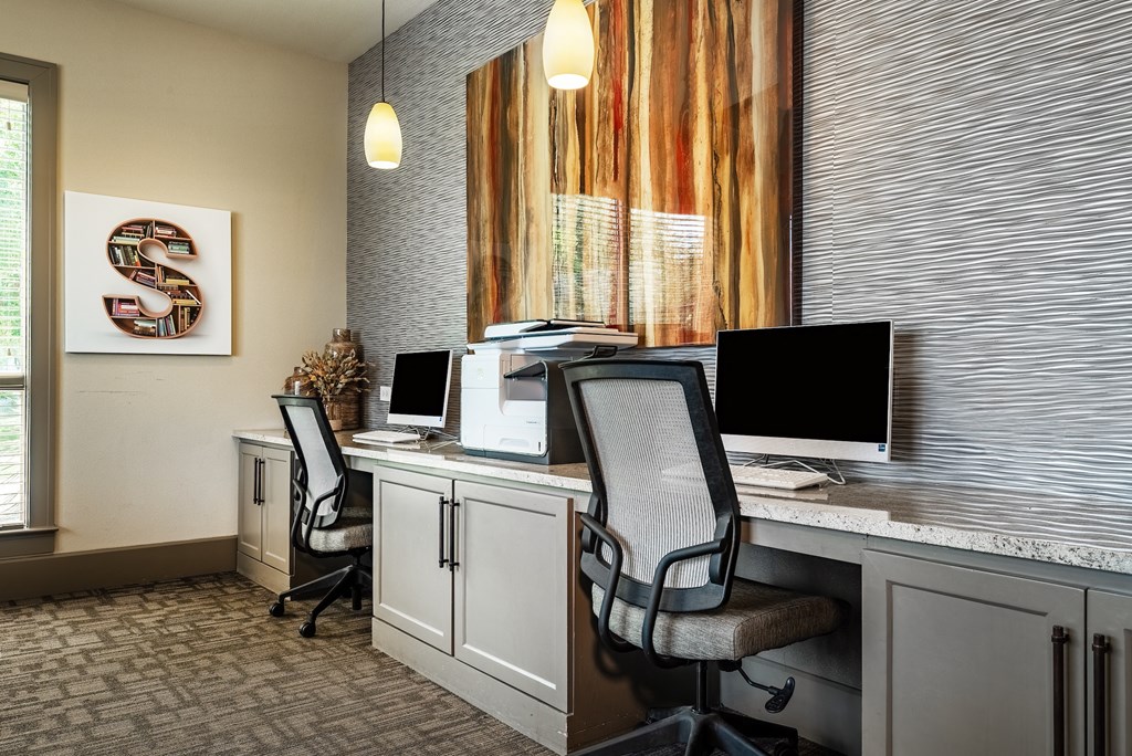 a desk with two computer monitors and two chairs