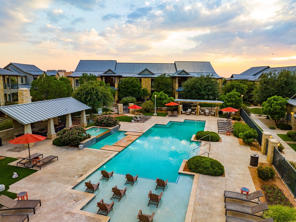 a swimming pool with lounge chairs and umbrellas in front of a brick building