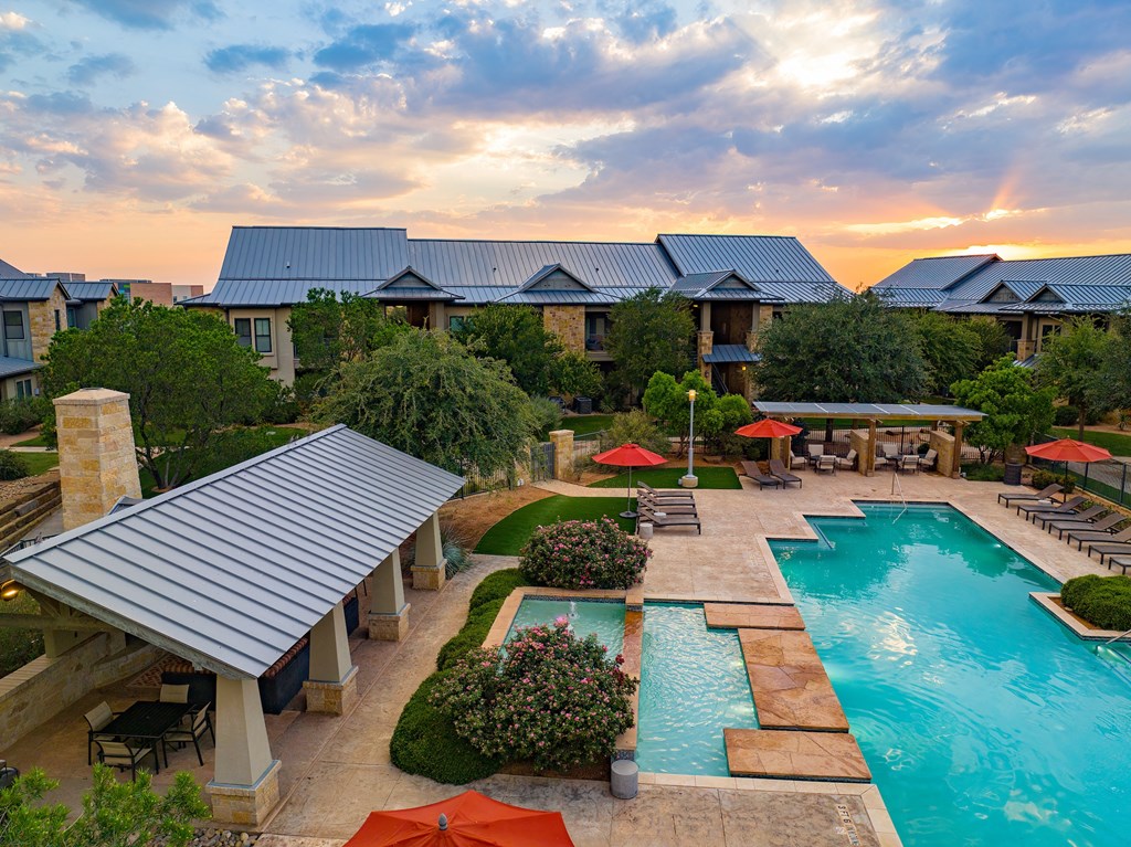 an aerial view of a resort style swimming pool with lounge chairs and umbrellas