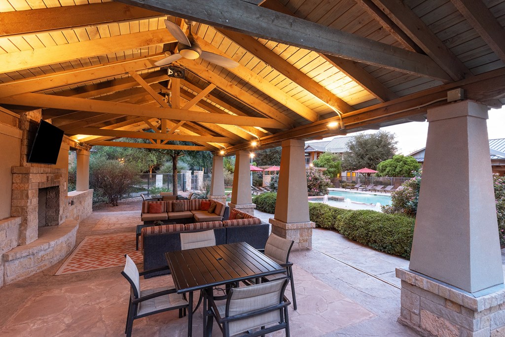 a covered patio with a fireplace and a wooden ceiling with exposed beams