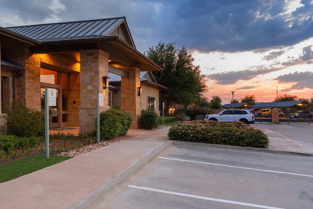 a parking lot in front of a building with a sunset in the background