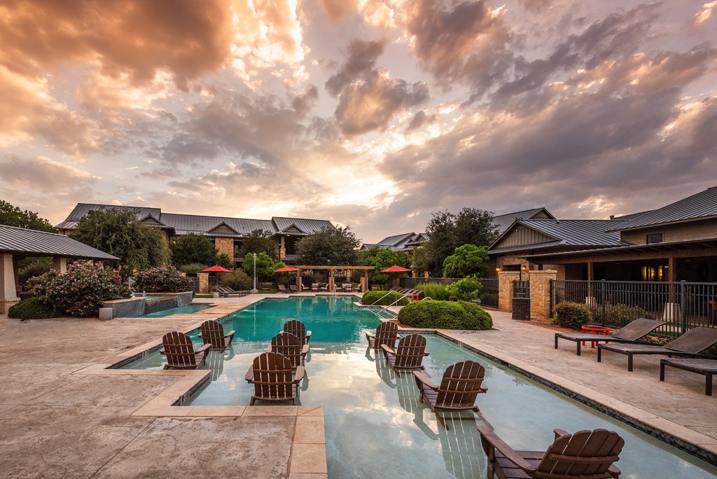 a swimming pool with chairs and umbrellas in front of a house