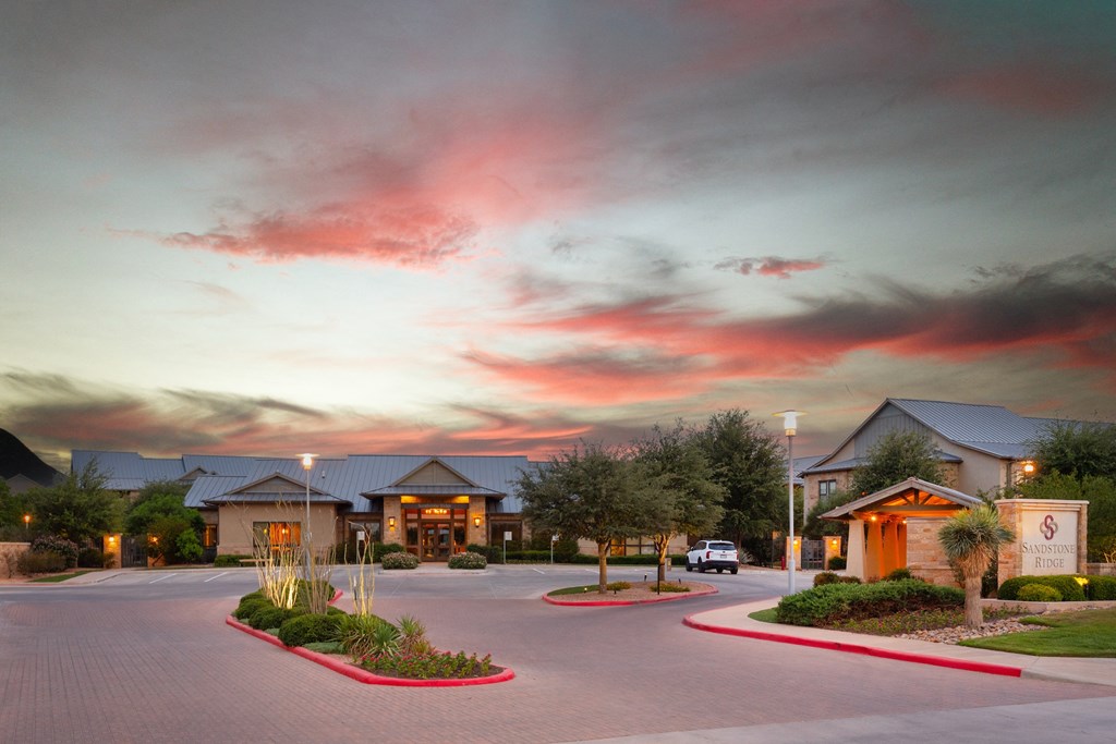 a building with a parking lot in front of it with a sunset in the sky