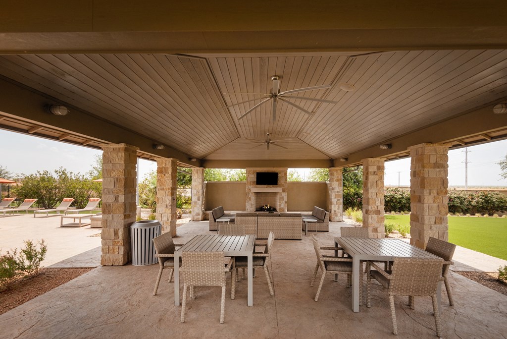 a covered patio with tables and chairs and a fireplace