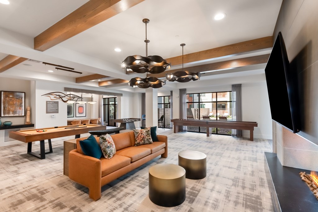 A modern living room with a brown sofa and a television on the right side.