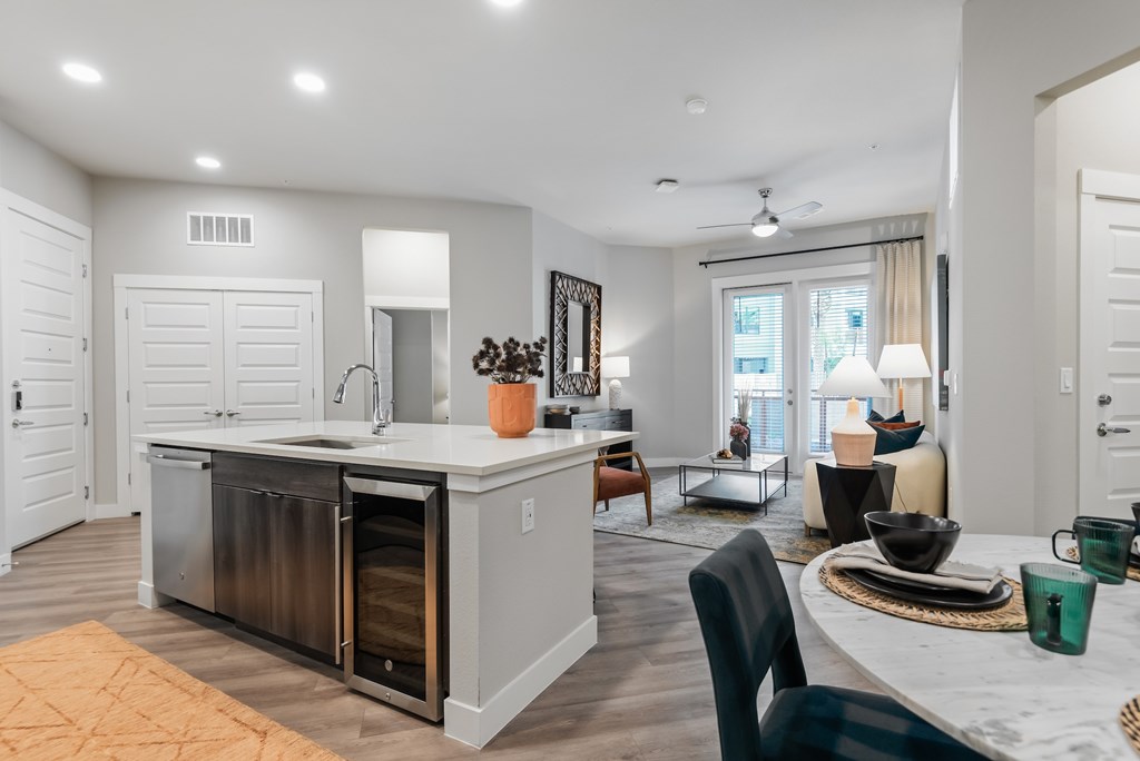 A modern kitchen with a large island and a dining area with a table set for two.