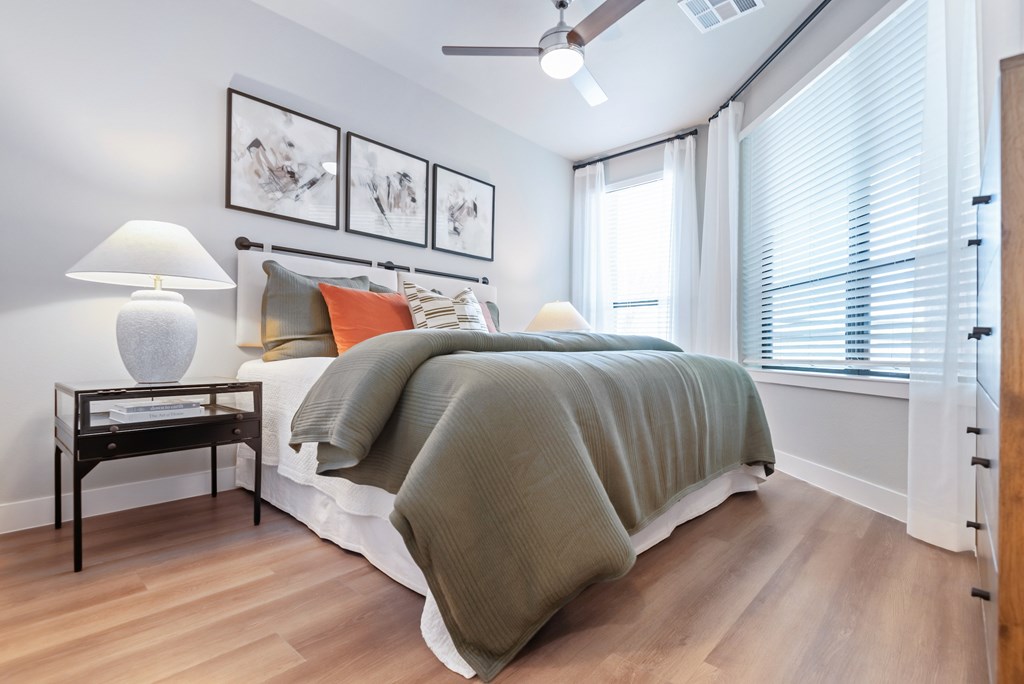 A bedroom with a bed, a nightstand with a lamp, and pictures on the wall.