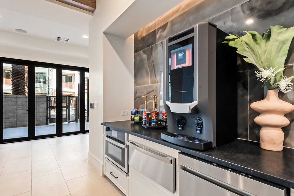 A modern kitchen with a black countertop and stainless steel appliances.