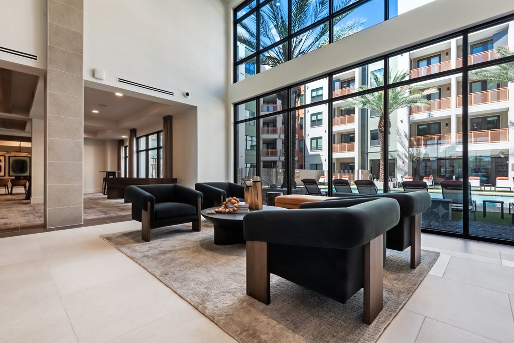 A modern living room with black furniture and a large window.