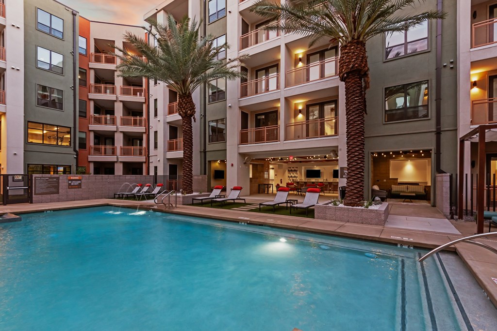 A swimming pool in front of a building with palm trees.