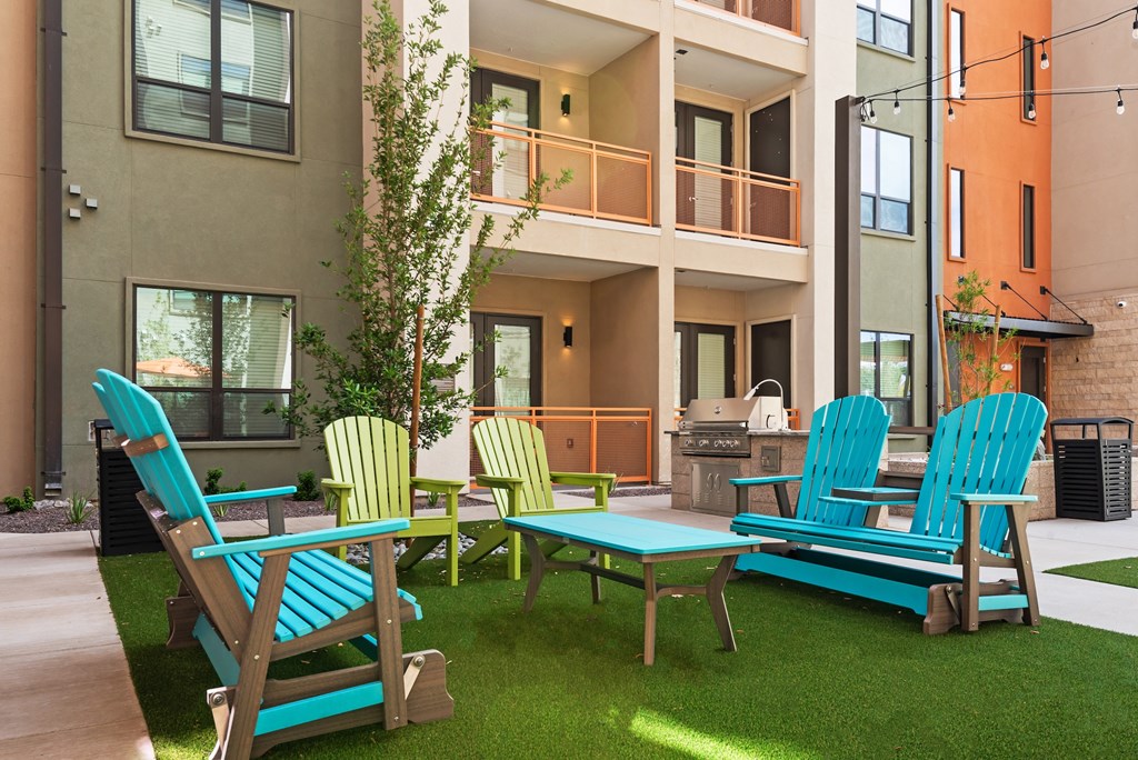 A set of four chairs and a table are set up on a lawn.