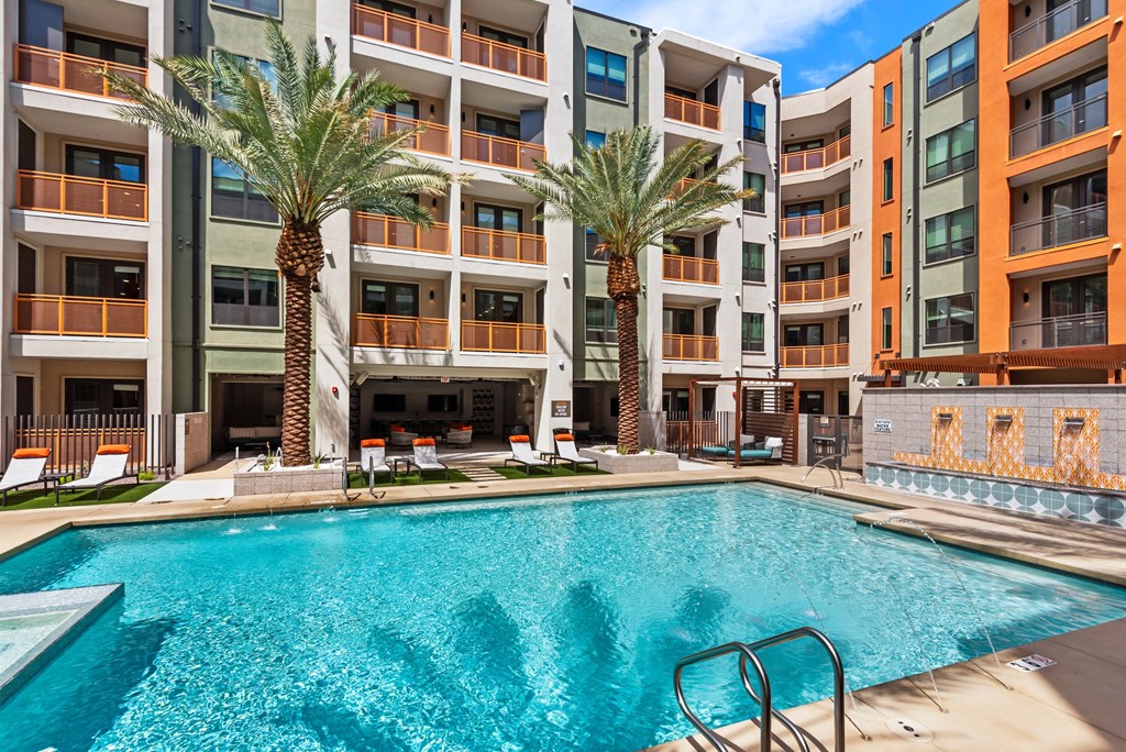 A swimming pool in front of a multi-story apartment building.