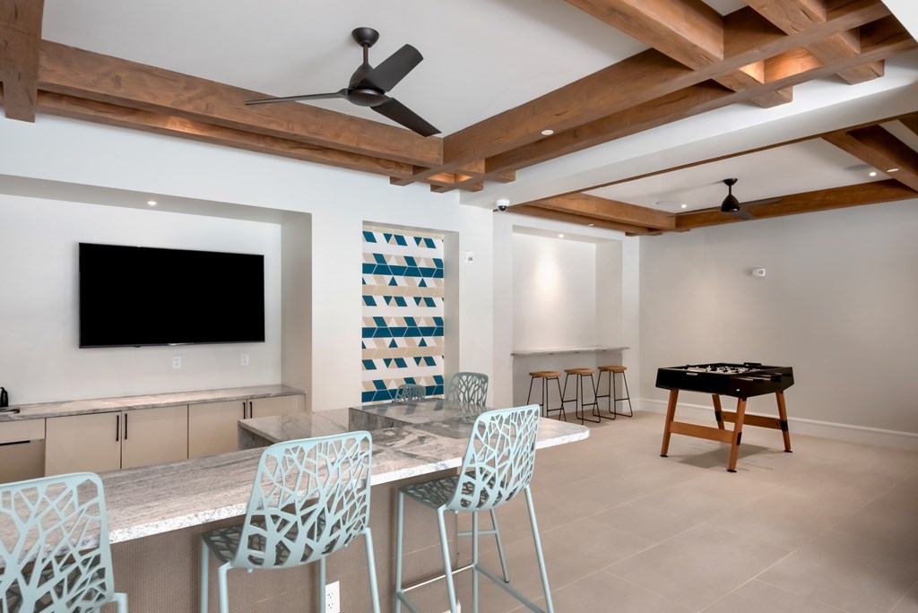 A room with a television, chairs, and a table.