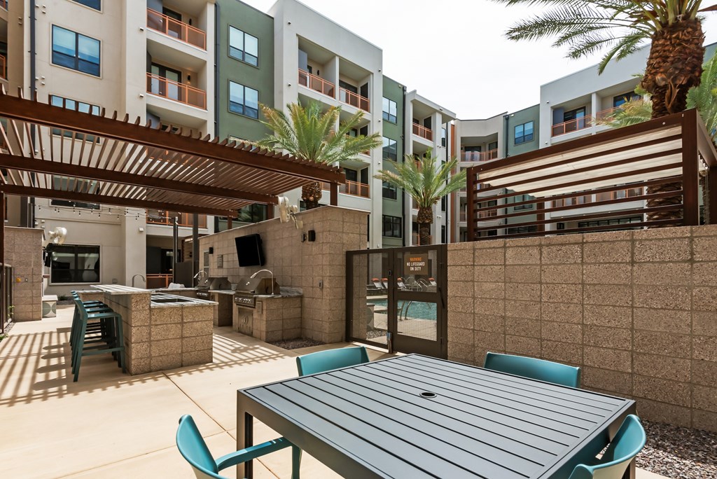 A patio with a table and chairs is surrounded by apartment buildings.