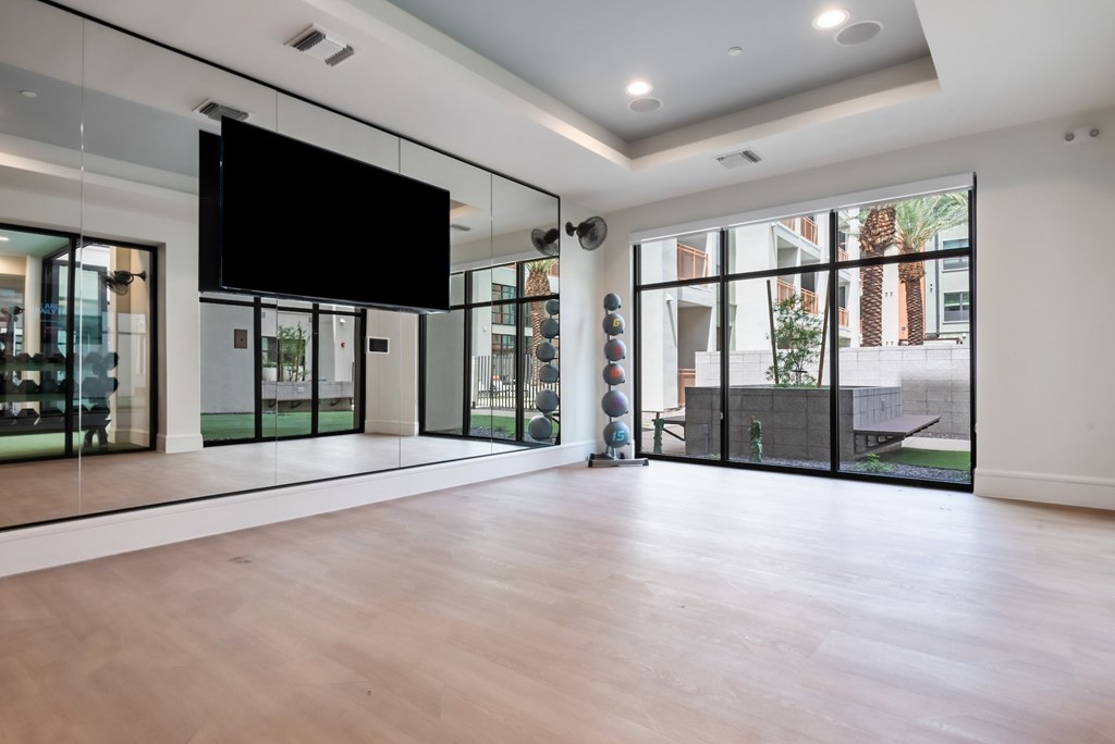 A spacious room with a television mounted on the wall and sliding glass doors.