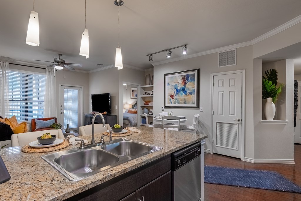 an open kitchen and living room with a granite counter top and a sink