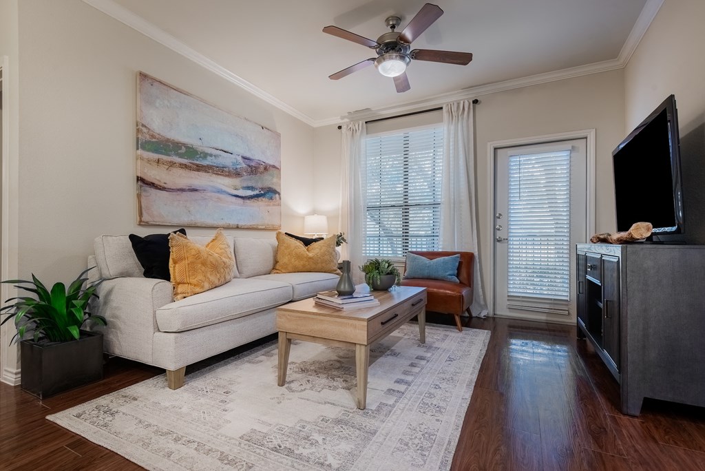 an empty living room with a ceiling fan and a television