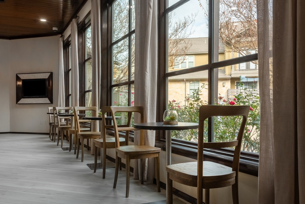 a row of tables and chairs in a room with large windows